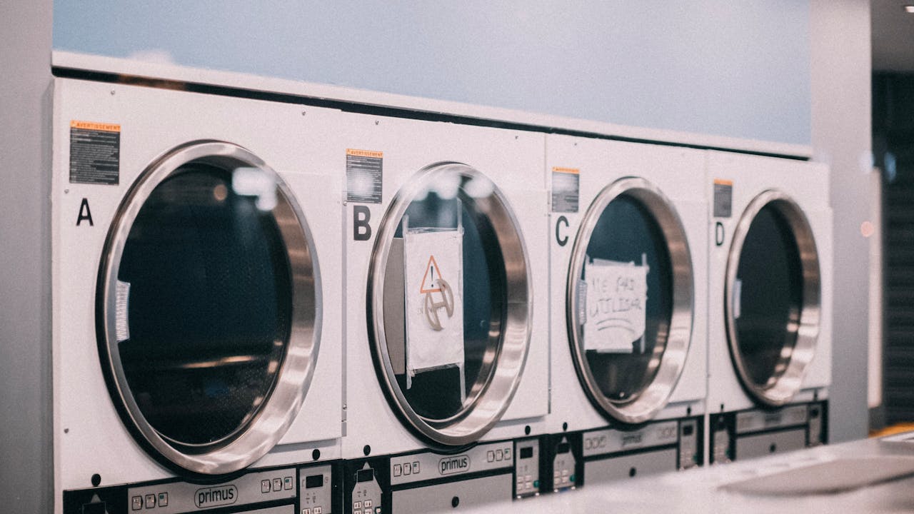 A series of industrial washing machines labeled A to D in a modern laundromat setting.