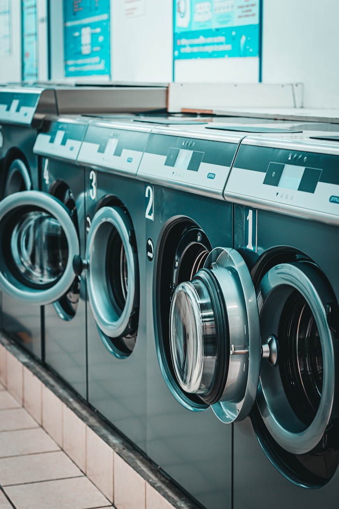 Contemporary laundromat featuring a row of stainless steel washing machines with open doors.